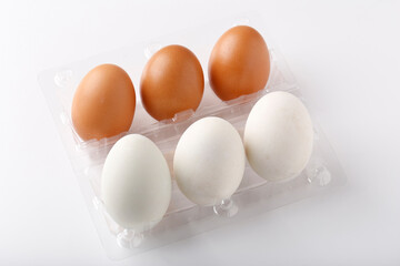 3 Duck eggs (White color) and 3 chicken eggs (Brown color) arranged in plastic packaging boxes for sale.