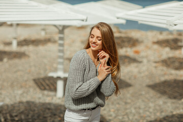 Young beautiful woman with long hair in a gray sweater on the street