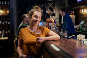 Portrait of smiling woman with beer in the bar - obrazy, fototapety, plakaty