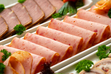 Platter of fresh meat cold cuts with vegetables.