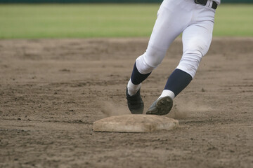 野球の試合中に次の塁を狙い全力疾走する野球選手