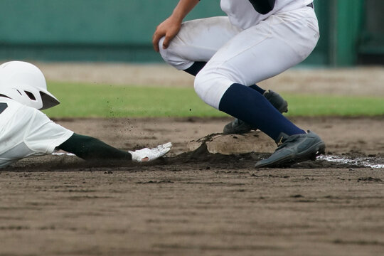 野球の試合中に一塁ベースに帰塁する走者とタッチしようとする一塁野手