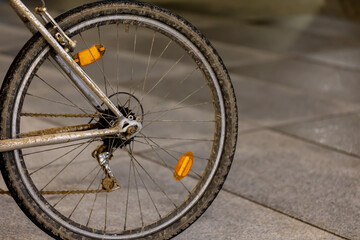 Fototapeta premium Old and dirty mountain bike used for commuting parked in the bike rack at city center. Picture taken in the evening, poor light coming form the street lights.