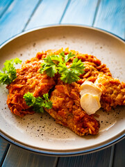 Fish dish - fried fish fillet in vegetable sauce on wooden table
