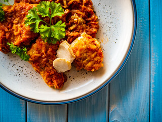 Fish dish - fried fish fillet in vegetable sauce on wooden table
