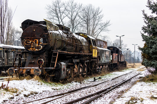 Old, rusty, demolished steam locomotive standing on the side track of the train station. Picture taken in cloudy winter day.