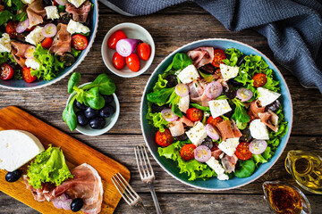 Tasty salad - prosciutto di Parma, manouri cheese and fresh, green vegetables on wooden table