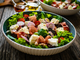 Tasty salad - prosciutto di Parma, manouri cheese and fresh, green vegetables on wooden table