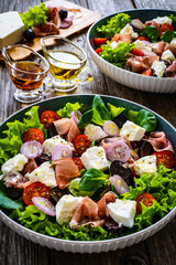 Tasty salad - prosciutto di Parma, feta cheese and fresh, green vegetables on wooden table