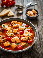 Fish soup with prawns on wooden table