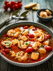 Fish soup with prawns on wooden table