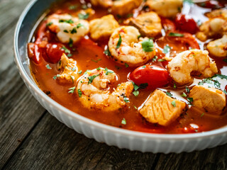 Fish soup with prawns on wooden table