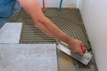 Man making using adhesive cement base the ceramic tile flooring