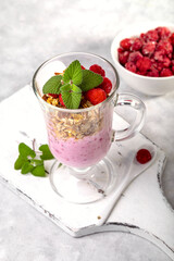 Raspberry smoothie and homemade granola in a transparent glass. Healthy breakfast or snack
