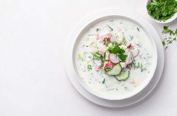 Summer, cold okroshka soup with vegetables, sausage, herbs and kefir on a white background. - obrazy, fototapety, plakaty