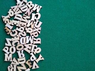 wooden letters of the alphabet scattered on a green background with space for text