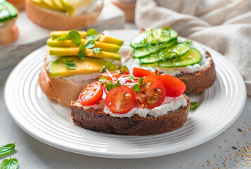 Rye and wheat toast with feta, cherry tomatoes, avocado and cucumber close-up.