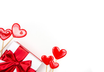 Gift with a bow and candy hearts on a white background. Congratulations, space for text. - obrazy, fototapety, plakaty