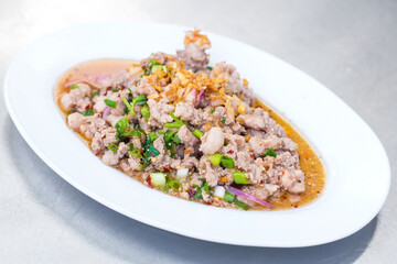 Spicy minced pork salad is traditional food of Northeast of Thailand. It contains minced pork, roasted rice, roasted chili and Thai herbs mixed together. It was put on white plate.