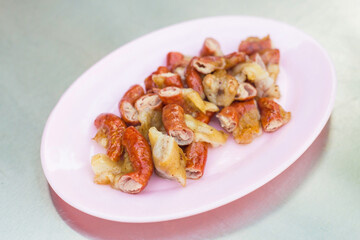 Tender and delicious grilled pork patties sliced ​​in pink plates on the table taste good, Northeast’s food of Thailand (Isaan food) is a street food in Thailand.