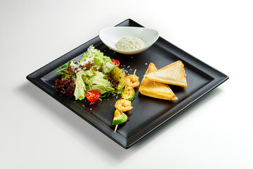 Breakfast toast with cheese and shrimp, salad in a black plate on a gray background