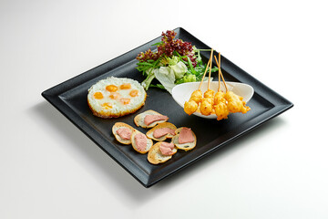 Breakfast scrambled eggs with shrimp and toast and salad in a black plate on a gray background