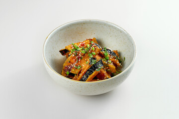 Fried eggplant wok in sweet and sour sauce in a blue plate. Gray background. Close-up