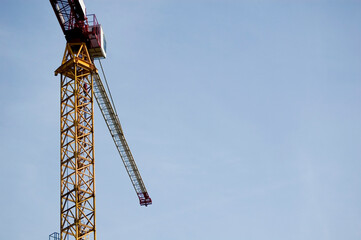 Fototapeta premium Large construction site crane working on a building complex with clear blue sky.