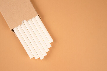 White paper straws in kraft paper box on kight brown background with copy space. Biodegradable drinking straws. Sustainable lifestyle and zero waste concept, mockup image for your design - obrazy, fototapety, plakaty