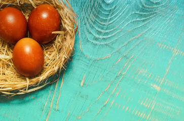 Brown Easter eggs in a nest on an aquamarine wooden background. Selective focus, the concept of Easter