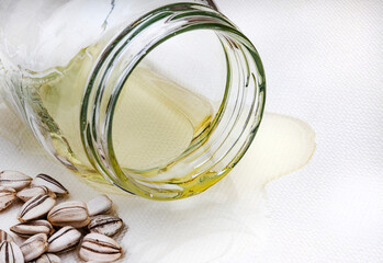 Sunflower oil spilling out of plain clear jar on a white surface with sunflower seeds