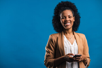 Portrait of a curly-haired African woman, holding a mobile phone.