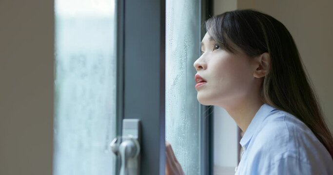 woman look through rainy window