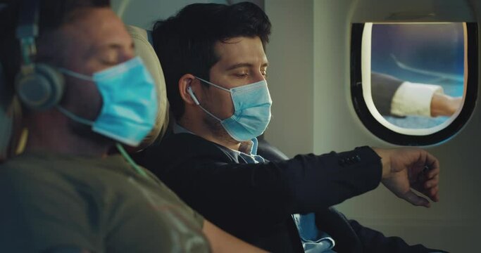 Surrealistic shot of passengers in cabin of aircraft with medical masks watching out of window and see funny scene with business man flying with them while traveling by plane.
