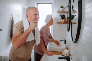 Senior couple in bathroom, brushing teeth and washing, morning routine concept.