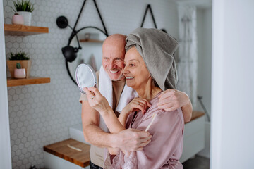 Senior couple in love in bathroom, looking at mirror and smiling, morning routine concept.