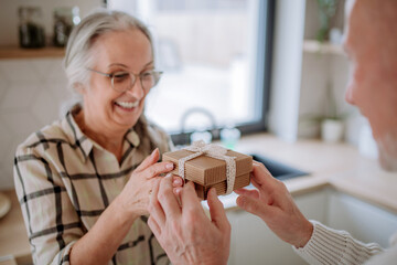 Happy senior woman getting present from her husband.