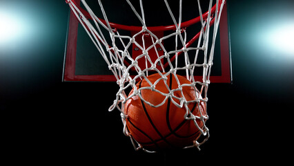 Fototapeta na wymiar Basketball going through the basket on black backgorund