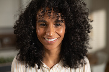 Cinematic authentic close up shot of young happy attractive brazilian woman is smiling in camera in kitchen at home.	