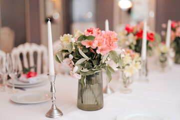 Candles and vase with white roses placed on round table near wineglasses during romantic date in garden