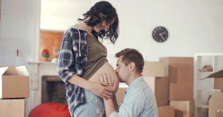 Happy husband kiss belly of pregnant wife