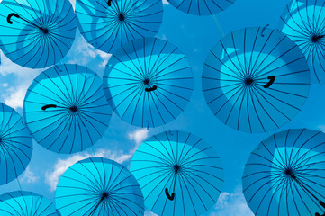 Fototapeta na wymiar Umbrella sky background. Blue umbrellas hanging bottom- up. Street decoration
