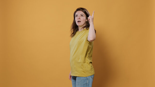 Portrait Of Smiling Woman Entering Room Having An Idea Thinking Being Spontaneous Touching Temples With Index Finger In Studio. Casual Young Person Showing In Frame Having Inspiring Thoughts.