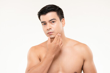 Handsome man touching his face checking for skin problems and wrinkles in white isolated background