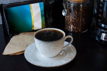 Coffee machine, a cup, a package, a jar full of coffee beans and a spoon of  filter coffee.