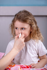 mom instills medicine into her sick child's nose