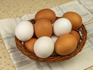 Fresh eggs in wicker basket on wood table. Close-up. Copy space.