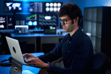 Broker Trader Business Man Working on Laptop in a Corporate Office. Multiple Monitors at Background