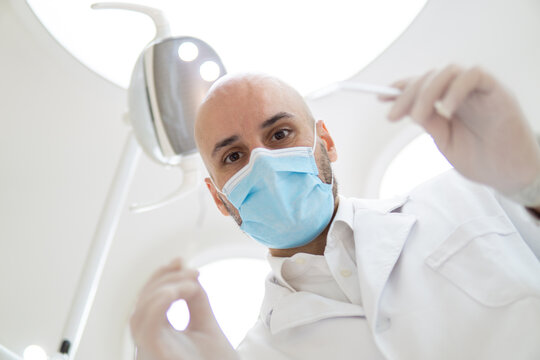 Skillful male dentist is treating human teeth