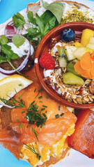 Brunch plate with scrambled eggs, salmon, yogurt, fresh fruit... Complete and healthy breakfast